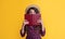 happy girl with frizz hair hiding behind book on yellow background