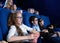 Happy girl in glasses eating popcorn and laughing in cinema