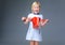 Happy girl on grey looking in red christmas shopping bag