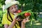 happy girl in hat in garden holds plate with vegetables, tomatoes, cucumbers, green onions and bites them. Proper nutrition,