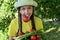 happy girl in hat in garden with plate of vegetables, tomatoes, cucumbers, green onions holds sprig of tomato in her mouth.