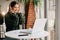 Happy girl in headphones with a laptop has a freelance job while sitting in a cafe. Cheerful woman with wireless headset