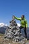 Happy girl hiker putting stones, small rocks on stone stack, high in mountains