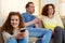 Happy girl holding television remote control with parents in background