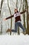 Happy girl in knitted cozy wear jumping in snowy winter forest. Christmas background. Attractive winter landscape. Jumping woman.
