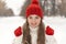 Happy girl in knitted sweater,red hat and mittens in winter park. Woman warms up in woolen clothes outdoors,cold weather