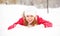 Happy girl laughs while lying on the snow in winter outdoors