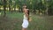 Happy girl with long hair in a white short dress runs through the park at sunset