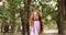 Happy girl with long red hair is walking in summer park on a white bridge.