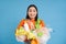 Happy girl looks at plastic garbage, sorting her waste for recycling station, smiling excited, blue background