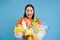 Happy girl looks at plastic garbage, sorting her waste for recycling station, smiling excited, blue background