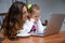 Happy girl and mother smiling watching notebook computer