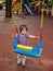 Happy girl playing on the swing on the Playground