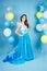 Happy girl in prom with helium air white, blue and yellow balloons. Portrait of a beautiful woman in a blue dress with a