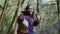 A happy girl in a purple olympium shows like and makes selfie on the background of the moss-covered trees