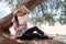 A happy girl reads a book on a tree, against the background of a sea beach. The person abstracted from everything