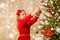 Happy girl in red dress decorating christmas tree