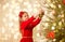 Happy girl in red dress decorating christmas tree