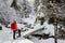 A happy girl, with a red jacket and a red backpack, crossing a wooden bridge, during a winter hiking trip