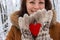 Happy girl with red wooden heart holding in hands in winter forest unfocused background. Valentines day and Christmas holidays.