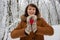 Happy girl with red wooden heart holding in hands in winter forest unfocused background. Valentines day and Christmas holidays.