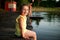 Happy girl rests on a pier in the lake beach at sunset. Leisure in heat summer days