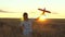 Happy girl runs with a toy airplane on a flower field. children play toy airplane. teenager dreams of flying and