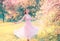 Happy girl in short flying gentle pink dress laughs joyfully, doll princess whirls in bright yellow spring garden with