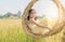 Happy girl sits in wicker swing among the golden rice fields