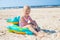 Happy girl sitting and laughing on an inflatable crocodile toy at the beach sunny day