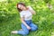 Happy girl smiling outdoor. Beautiful young brunete woman with brown hair resting on park or garden green grass background.