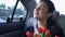 Happy girl sniffing flowers sitting in car, satisfied taxi client enjoying ride