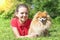 Happy girl with spitz lying on grass, looking at camera. day in life of senior, adult, elderly dog with owner. pet adoption.