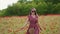 Happy girl in sunglasses, red dress runs to camera across scarlet poppies field