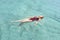 Happy girl swims in the pool. Top view of a girl in the pool, a stylish girl in a red swimsuit relaxes. Travel, rest, sun, summer