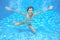 Happy girl swims in pool underwater, active kid swimming and having fun