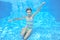 Happy girl swims in pool underwater, active kid swimming and having fun