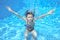 Happy girl swims in pool underwater, active kid swimming and having fun