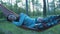 Happy girl swinging on a hammock in the park. Beautiful young woman smiling lying on a hammock.