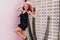 Happy girl with tanned skin dancing in summer black dress. Pink-haired woman jumping near cactus an