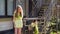 Happy girl teenager descending from stairs porch of country house at summer sunshine background. Young girl going down