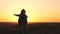 Happy girl traveler with a backpack whirls at sunset with her arms wide open to the sides. A woman on a tourist is