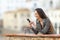 Happy girl using a smart phone in a balcony in a town