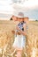 Happy girl walking in golden wheat,with her back, outdoor lifestyle. Freedom concept. Cute little girl in summer field.takes bread