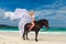 Happy girl walking with horse on a tropical beach