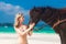 Happy girl walking with horse on a tropical beach