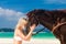 Happy girl walking with horse on a tropical beach
