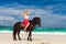 Happy girl walking with horse on a tropical beach