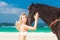 Happy girl walking with horse on a tropical beach