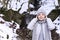 Happy girl in a warm jacket and hat stands in a snowy forest. The concept of tourism and travel. Copy space